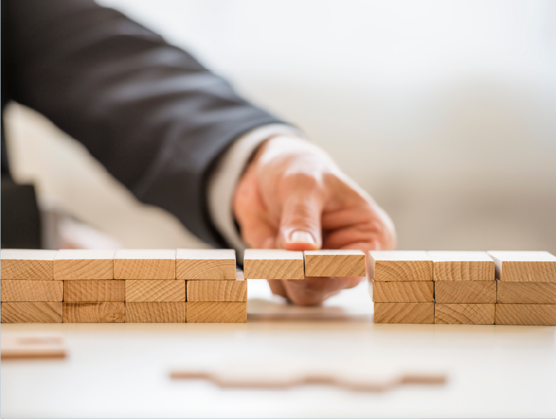 Building blocks to the right and left with a person holding a bridge of blocks between symbolising the gap that is bridged by construction recruitment agencies during labour shortages