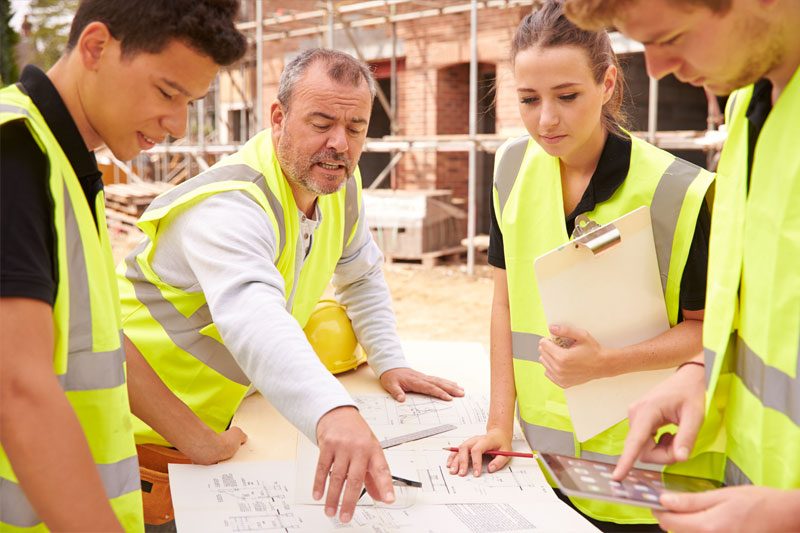 Construction workers gathered around construction plans