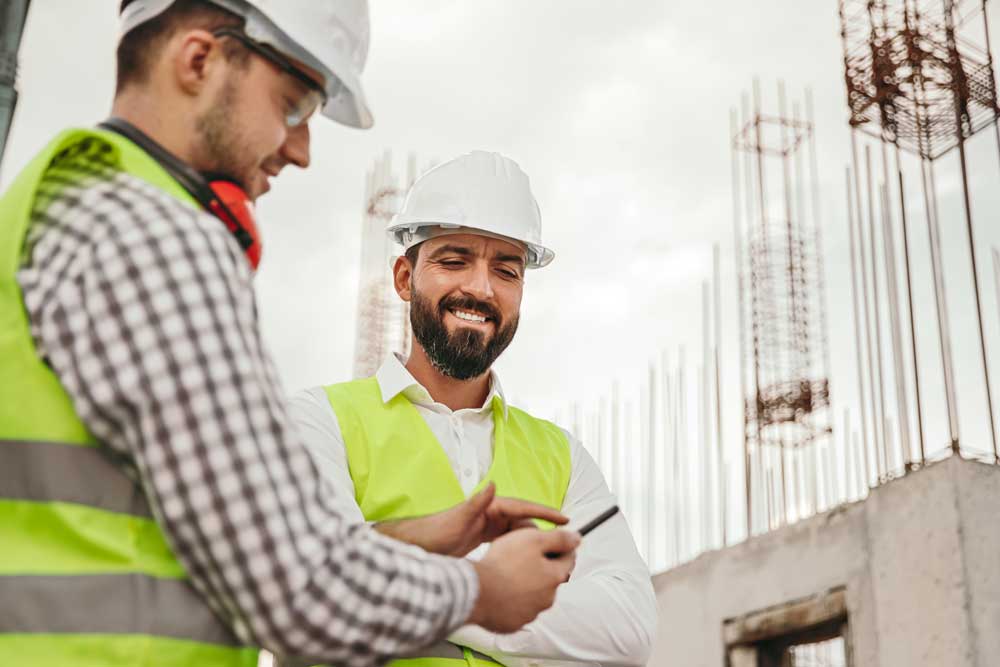 Construction workers on sitewearing PPE a white hard hat and high visibility jacket looking up their career in construction