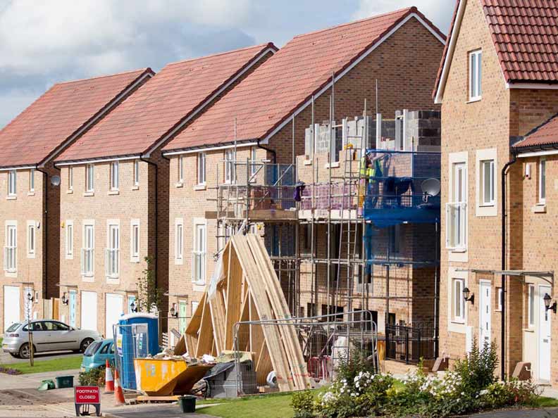 Street with finished houses and one still in construction due to labour shortages