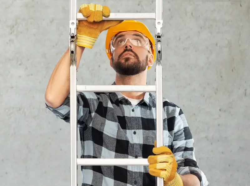 Construction labourer shown climbing a metal ladder from the bottom to top of the image.