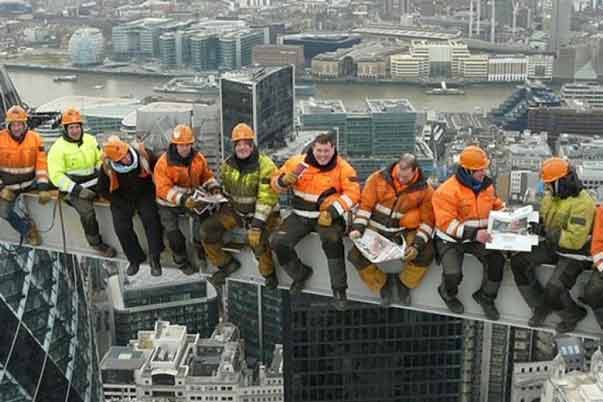 Construction workers sitting on a steel girder high over a city