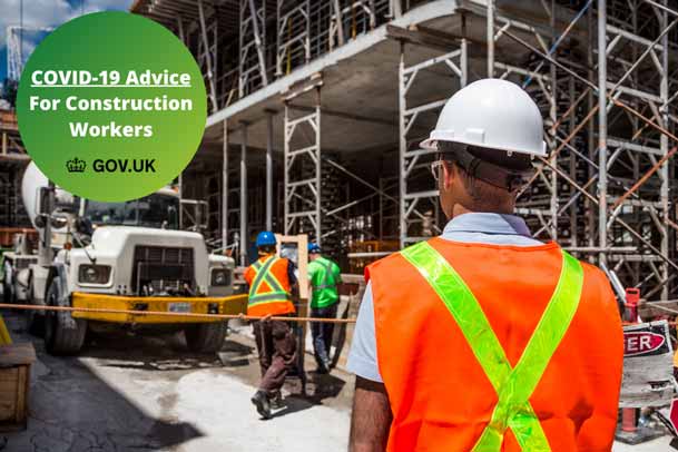Construction site with a construction worker in a high vis showing a covid-19 badge for construction workers advice