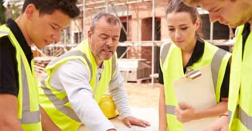 Construction workers gathered around construction plans