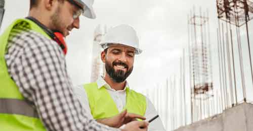 Construction workers on sitewearing PPE a white hard hat and high visibility jacket looking up their career in construction