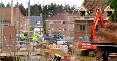 Construction housing site showing workers on scaffolding on the side of a building