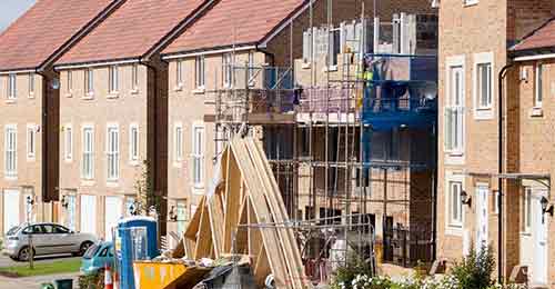 Street with finished houses and one still in construction due to labour shortages