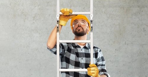 Construction labourer shown climbing a metal ladder from the bottom to top of the image.