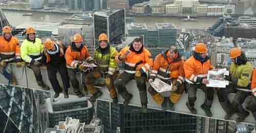 Construction workers sitting on a steel girder high over a city