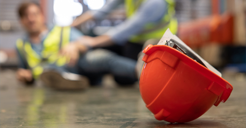 Construction worker fallen on the floor with a hard hat in the foreground