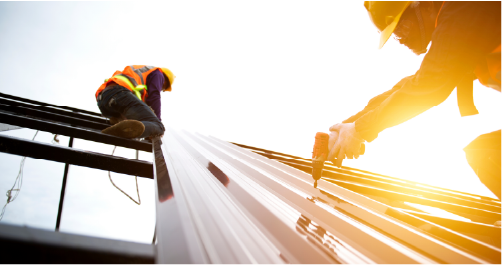 Construction workers laying roofing sheet on a roof holding tools for the job in a tough labour shortage