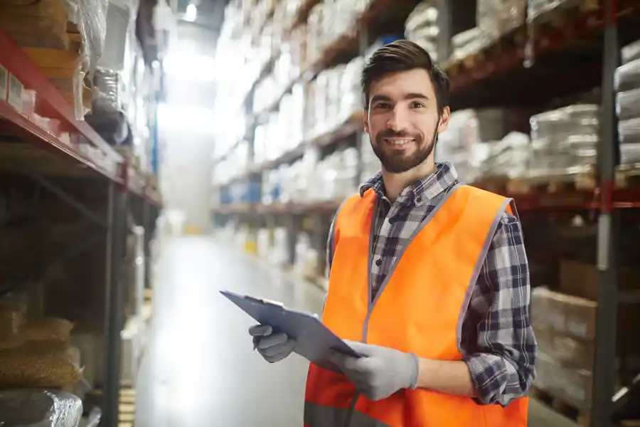 Warehouse worker in a high visibility jacket holding a clipboard with the text RecruitEasy's ultimate guide to thriving in the warehousing and logistics industry