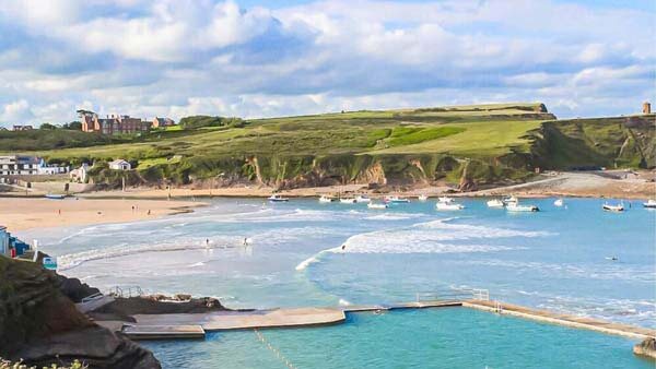 Aerial view of Bude beach showing the waves coming towards the beach with swimmers and boats across the bay