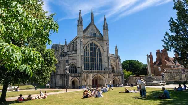 Winchester Cathedral in Hampshire with members of the public sat on the green