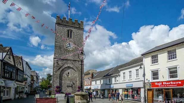 Newton Abbot picture showing St Leonard's Tower in the centre of town with various shops and buildings surrounding it