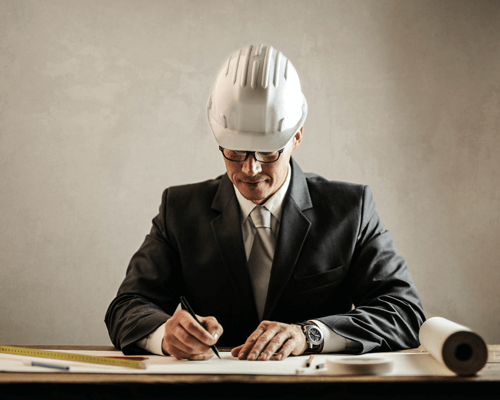 Two construction managers on a building site holding construction planning documents