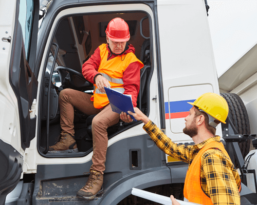 Two construction managers on a building site holding construction planning documents